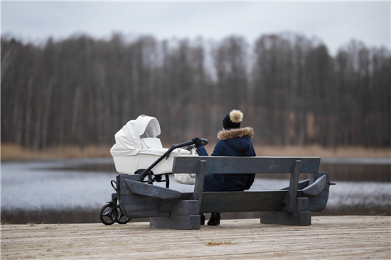 Image: Young mother, baby in pram gazing mournfully