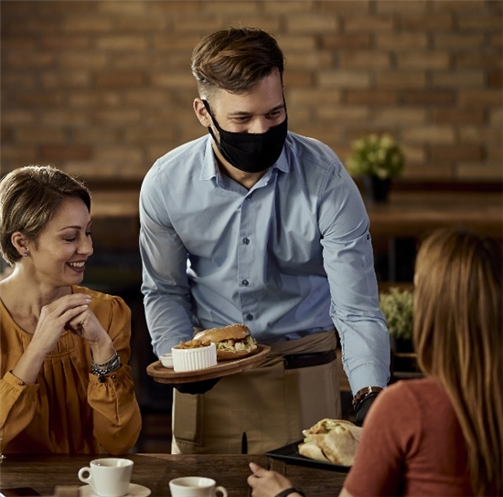 Image: Waiter serving inside wearing a facemask