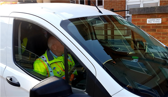 Image: A delivery driver turns of his engine while waiting for a colleague