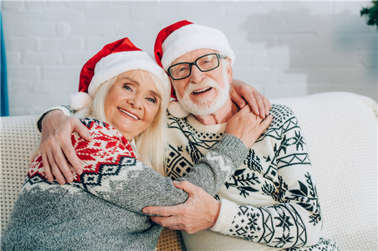 Image: Couple indoors wearing jumpers and santa hats, smilling